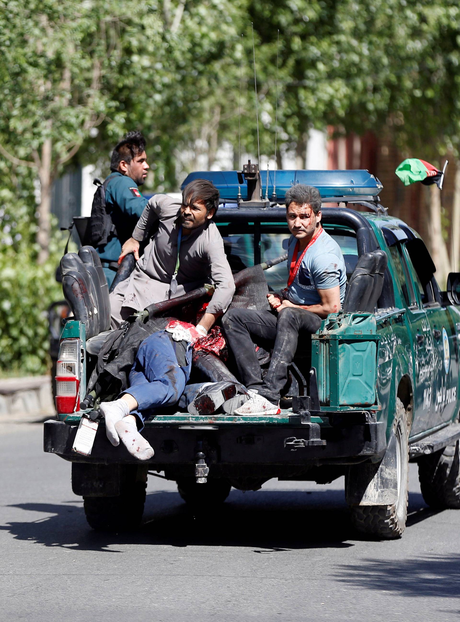 Afghan security forces carry injured men on a back of police car near the site a blast in Kabul, Afghanistan