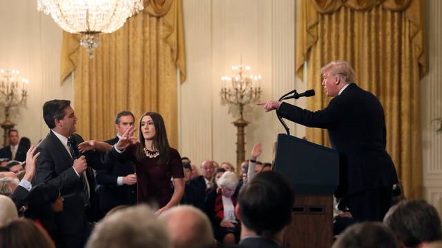 A White House staff member reaches for the microphone held by CNN's Jim Acosta as he questions U.S. President Donald Trump during a news conference in Washington