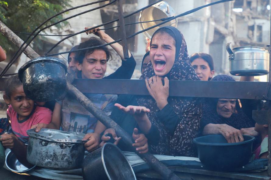 Palestinians wait to receive food from a charity kitchen amid hunger crisis, in Gaza City