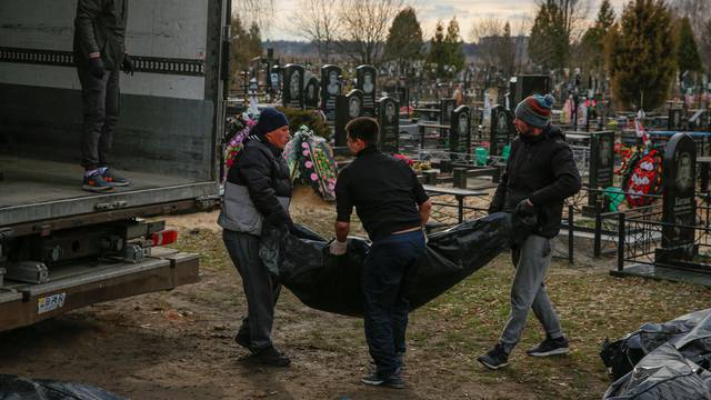 Funeral service employees unload bodies of civilians at a local cemetery in the town of Bucha