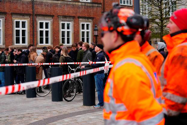 People stand behind a barrier tape during a fire at the Old Stock Exchange, Boersen, in Copenhagen