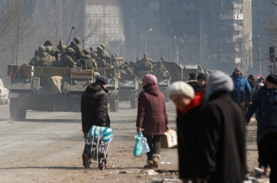 Service members of pro-Russian troops are seen atop of armoured vehicles in the besieged city of Mariupol
