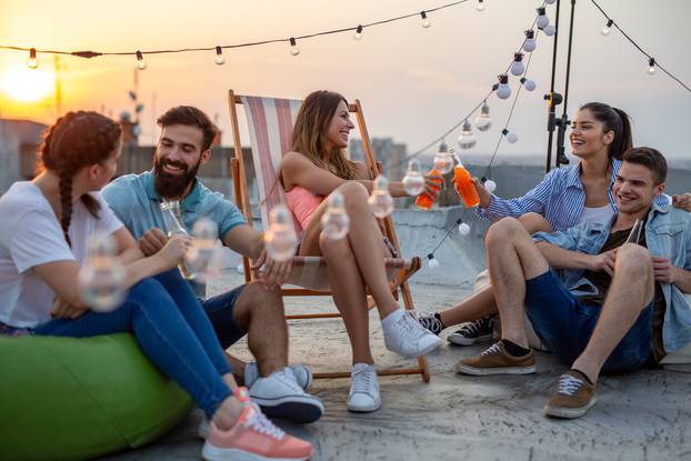 Happy friends toasting with drinks at a rooftop party