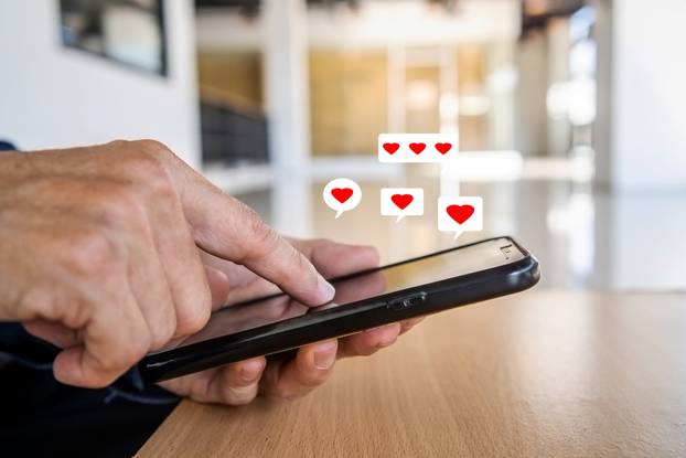 Man hand using smartphone with heart icon at office, He look mes