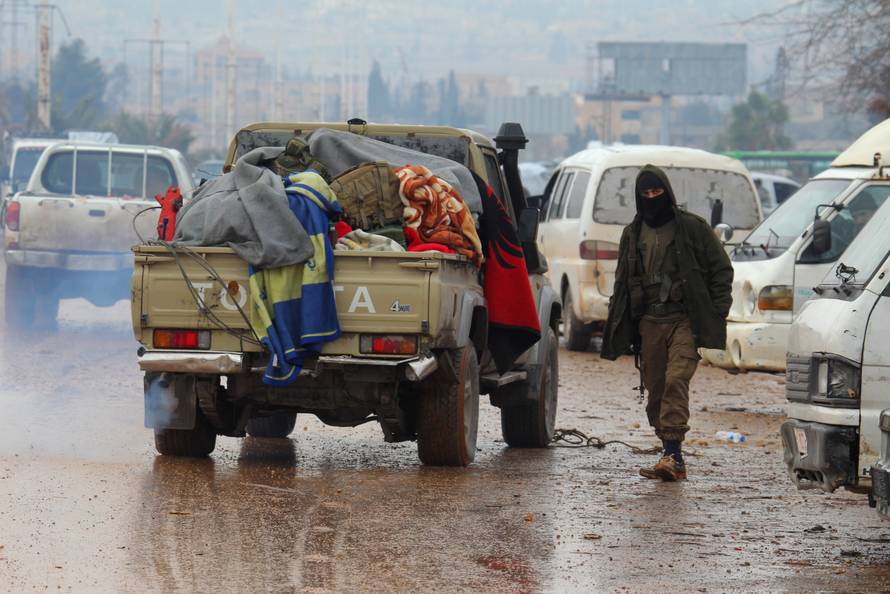 A rebel fighter stands near vehicles at insurgent-held al-Rashideen in the province of Aleppo