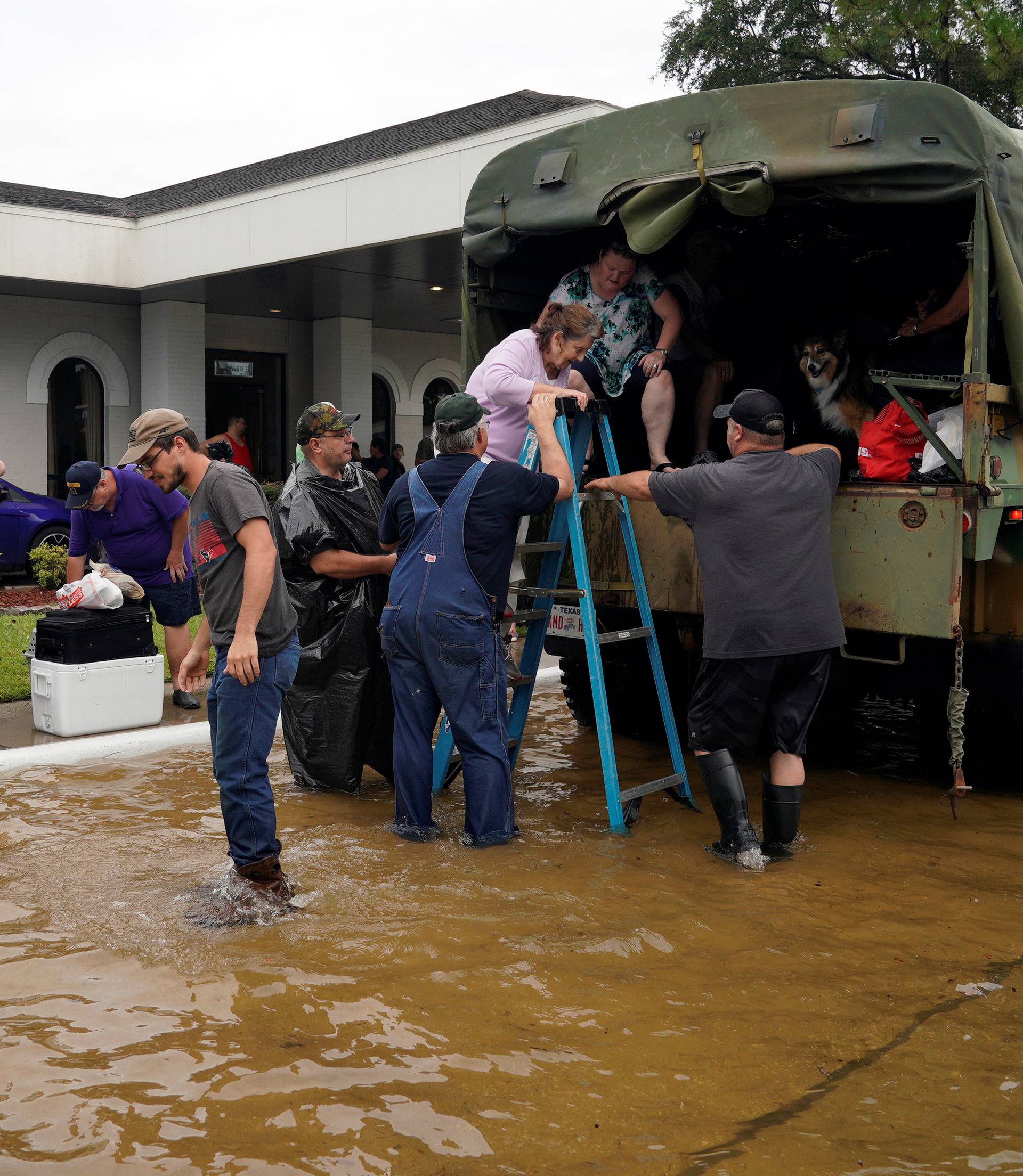 Volunteers load people into a collector's vintage military truck to evacuate them from flood waters from Hurricane Harvey in Dickinson