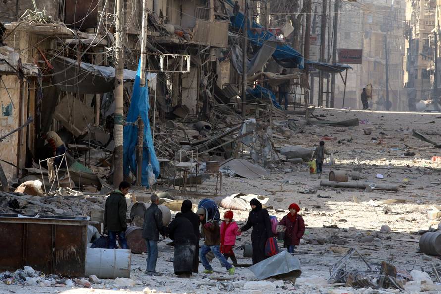 Syrians walk over rubble of damaged buildings, while carrying their belongings, as they flee clashes between government forces and rebels in Tariq al-Bab and al-Sakhour neighborhoods of eastern Aleppo