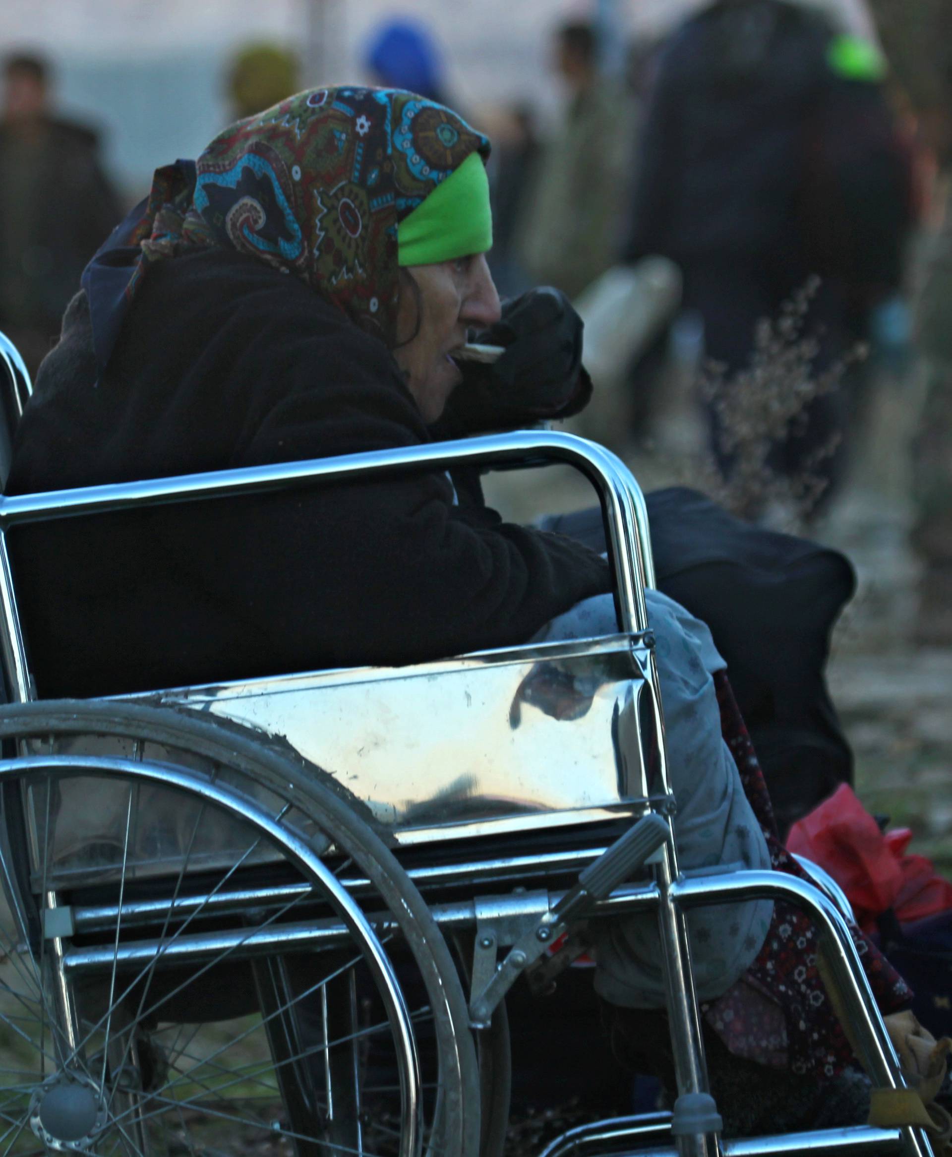 An evacuee from rebel-held east Aleppo, eats as she sits in a wheelchair upon her arrival with others to the town of al-Rashideen