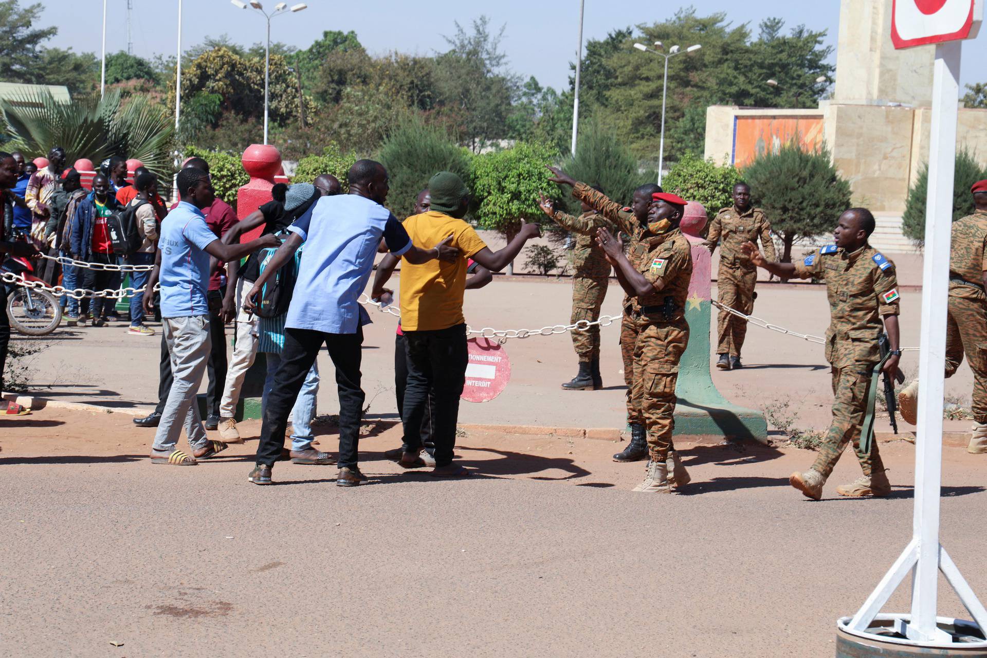 Army soldiers ask people to walk away as they gather outside Guillaume Ouedraogo army camp to show their support for the military after President Kabore was detained at a military camp in Ouagadougou