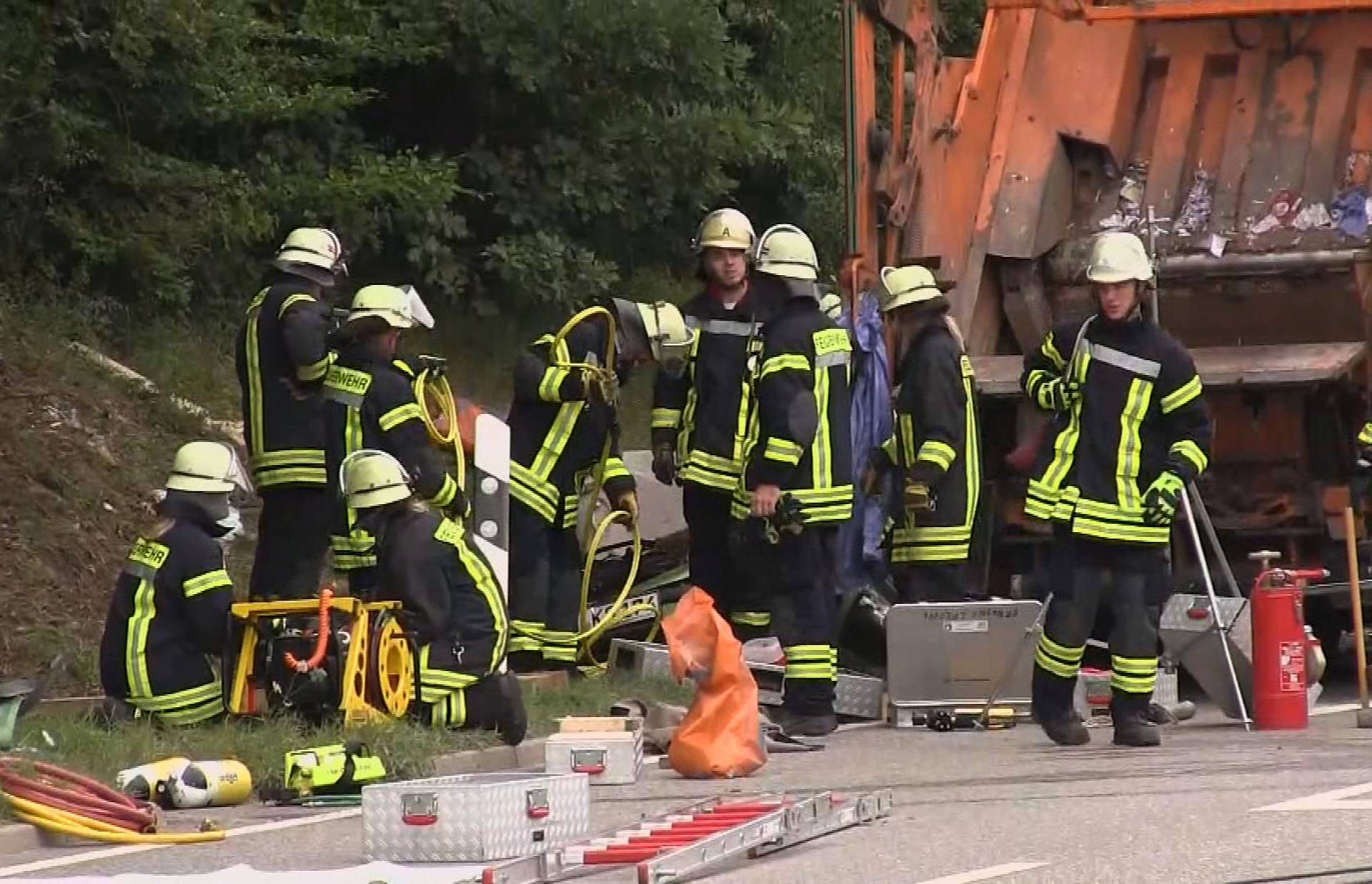 A still image taken from a video shows firefighters at a garbage truck which tipped over and landed on a car in Nagold