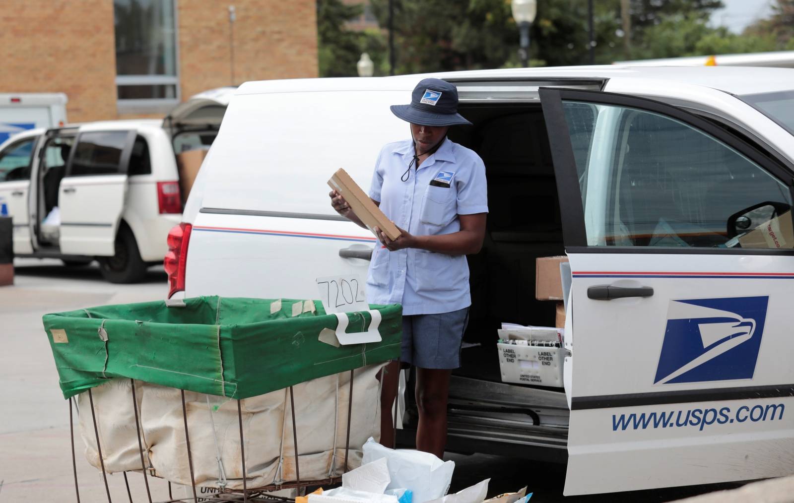 A United States Postal Service (USPS) worker loads mail into a delivery truck