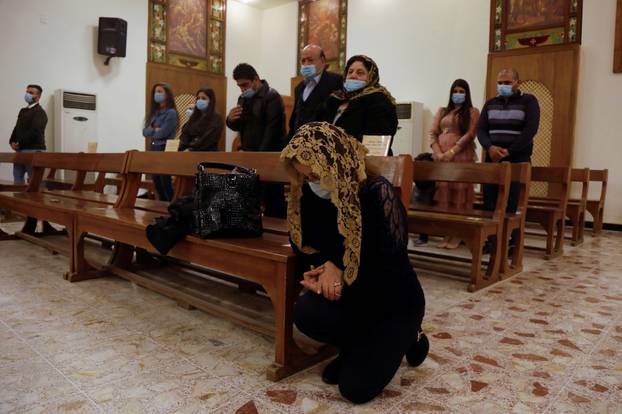 A Christian woman prays during a mass on Christmas at St. Elya Chaldean Church in Baghdad