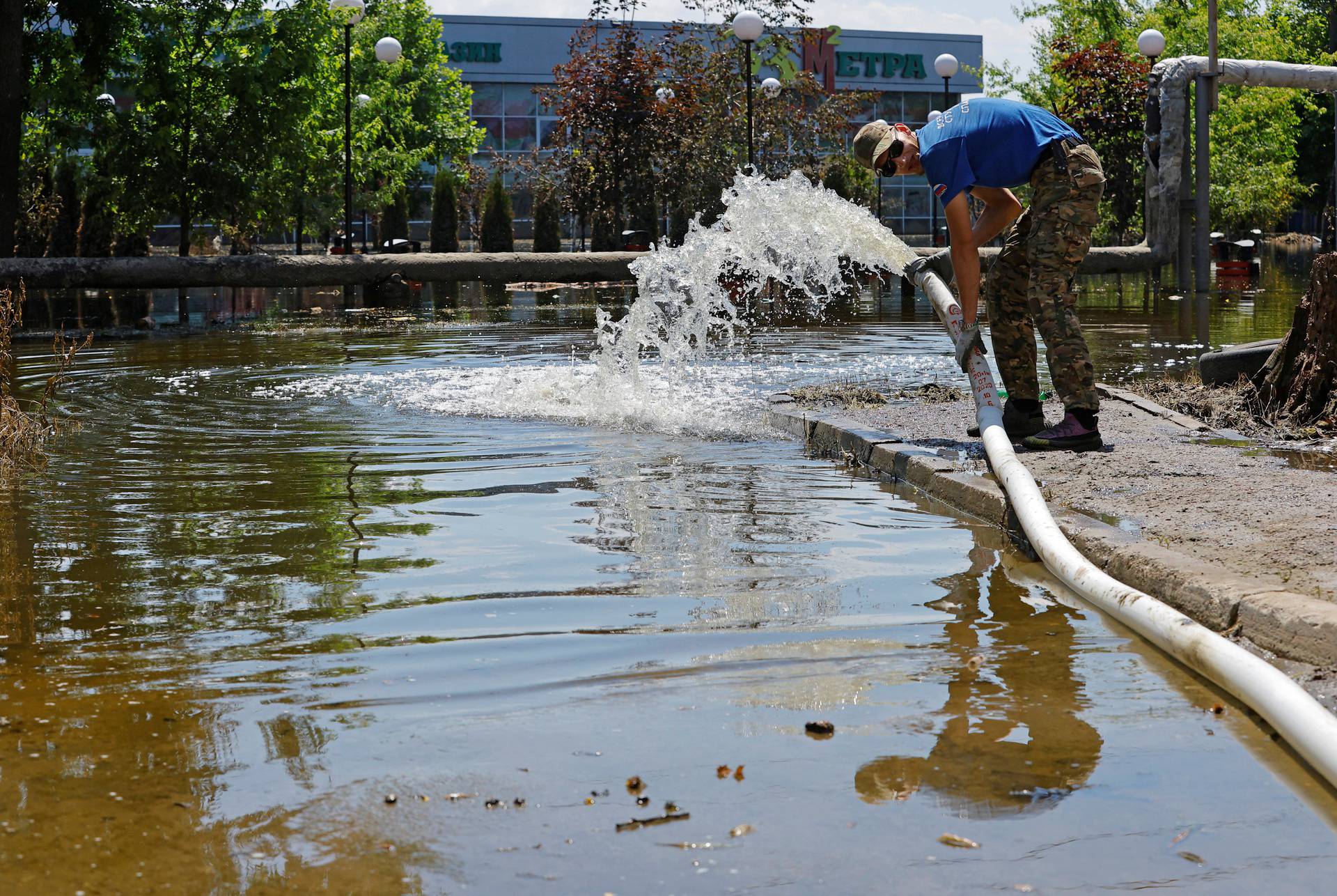 A member of the Russian Student Rescue Corps pumps water out of the basement of a building in Hola Prystan