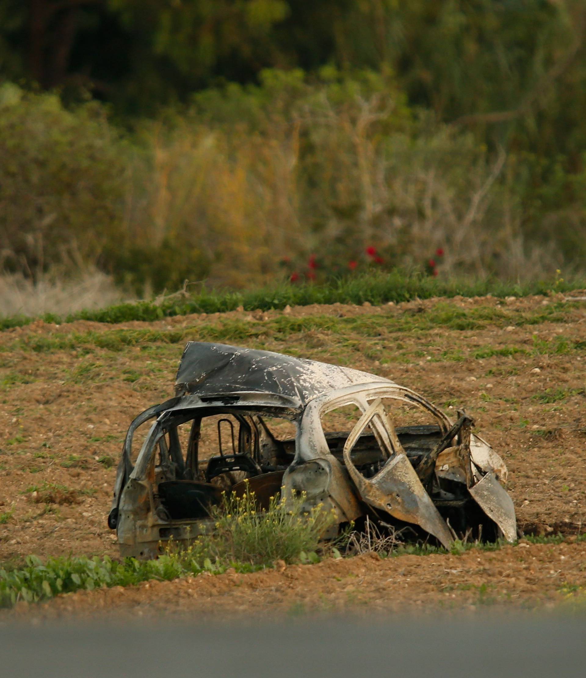 A forensics expert walks in a field after a powerful bomb blew up a car killing investigative journalist Daphne Caruana Galizia in Bidnija
