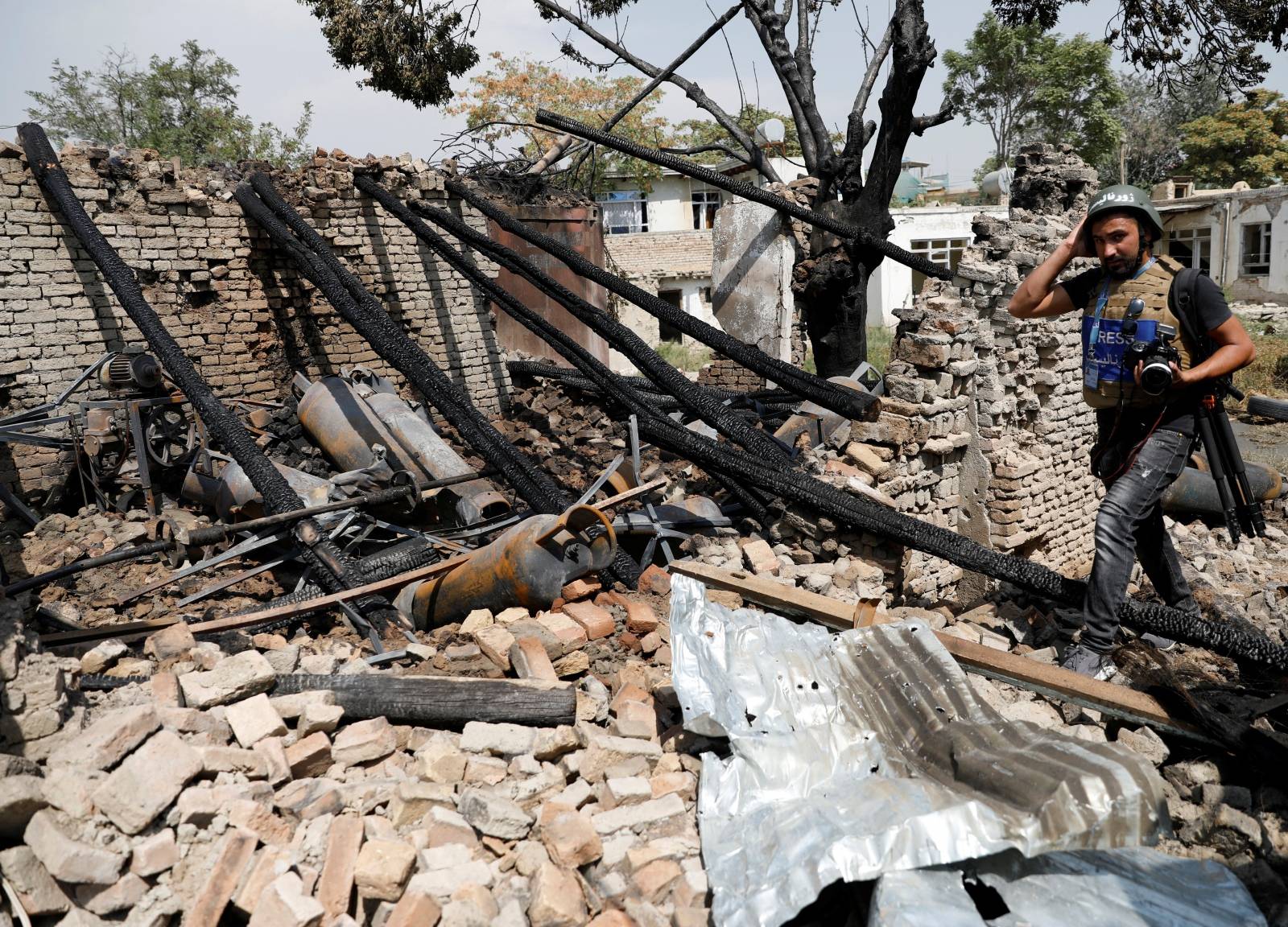 Journalist walks past a damaged shop after a blast in Kabul