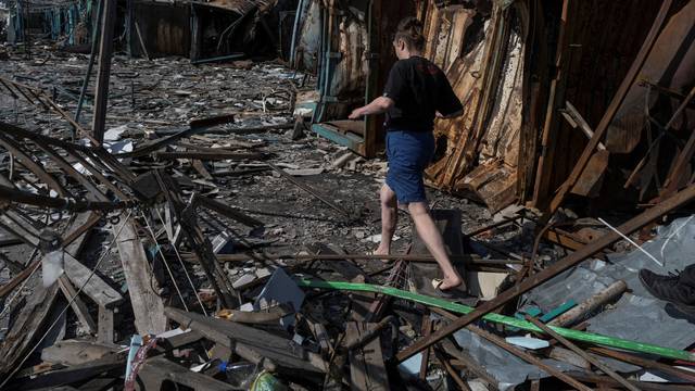 A local walks at a compound of a municipal market destroyed by a Russian military strike in the border town of Vovchansk