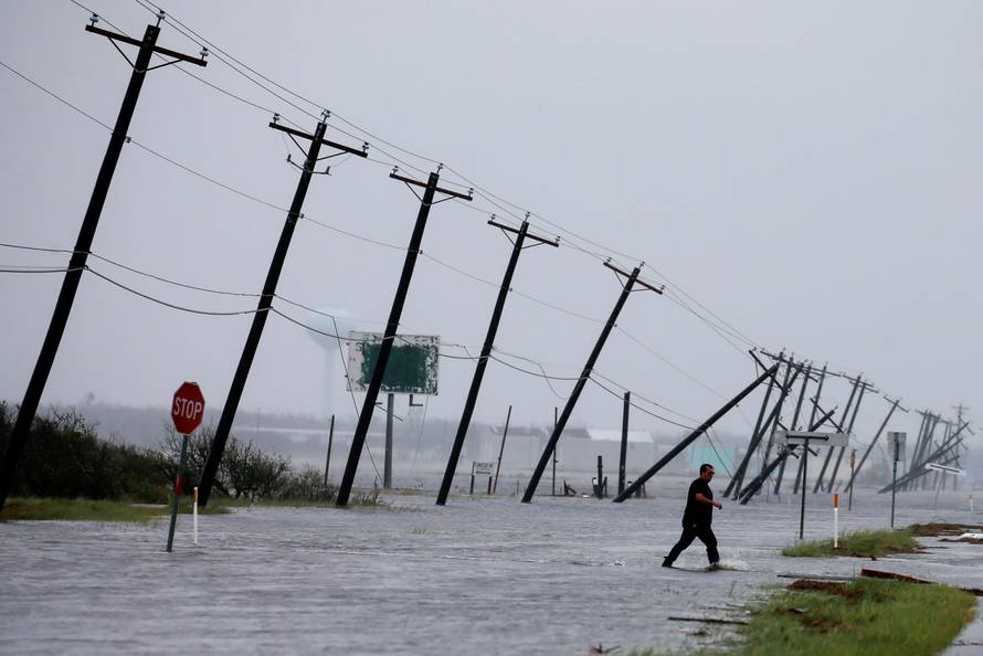 A man walks through floods waters after surveying his property which was hit by Hurricane Harvey in Rockport, Texas