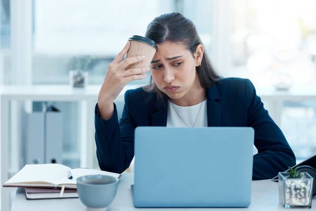 Could this day get any worse. a young businesswoman looking stressed out while working on a laptop in an office.