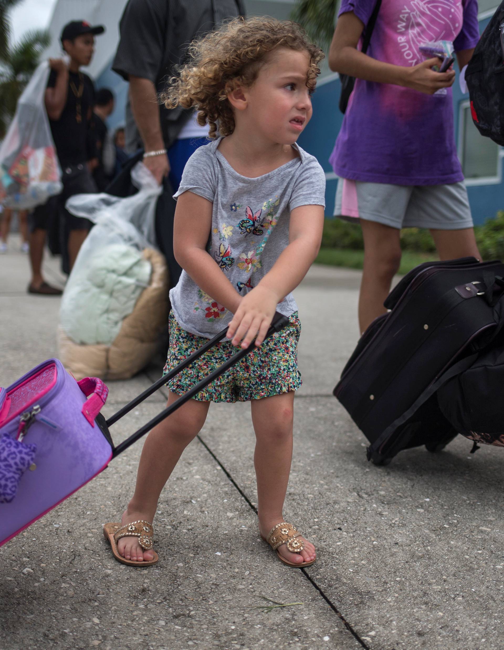 A girl carries her belongings into a shelter ahead of the downfall of Hurricane Irma in Estero, Florida