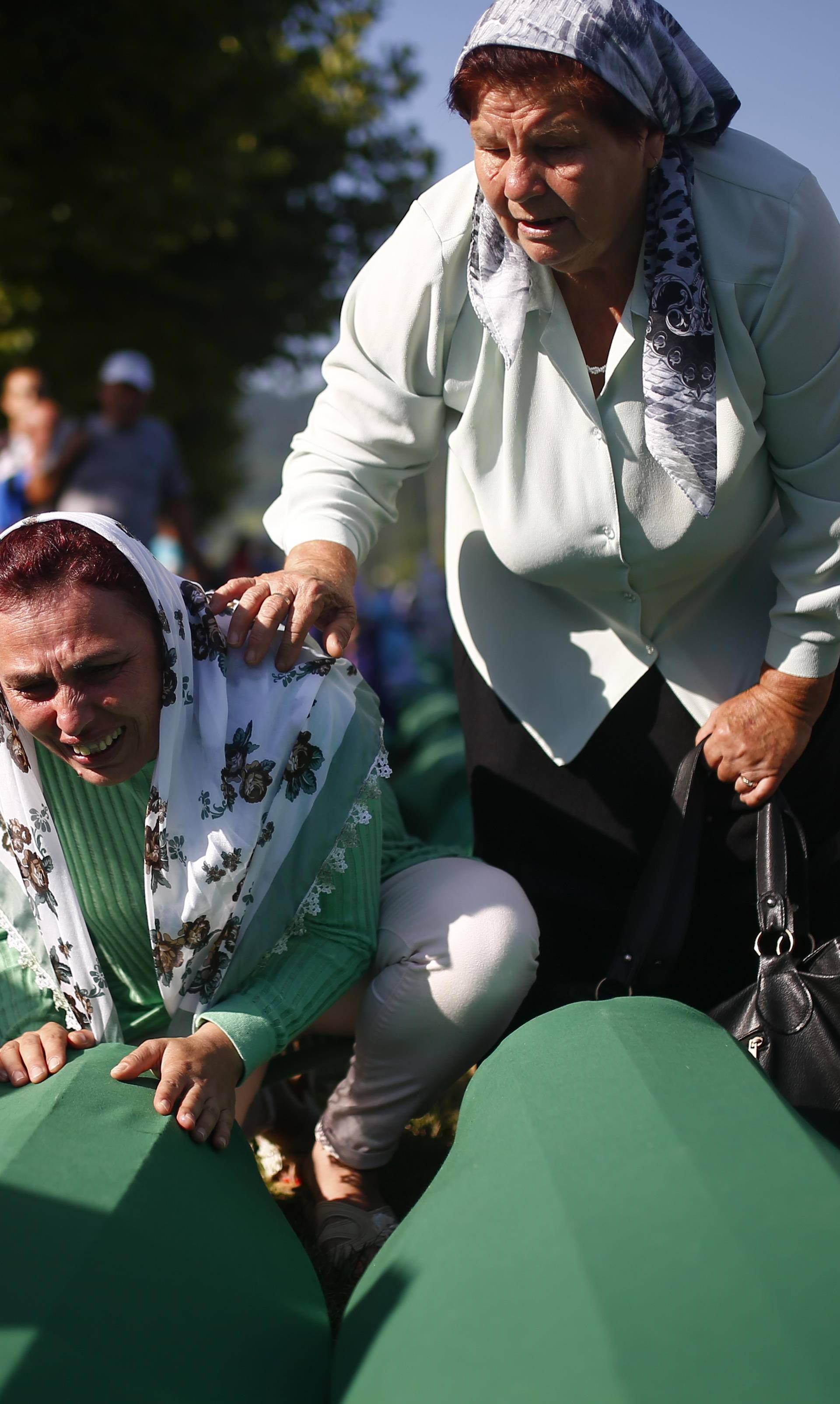 People mourn near coffins of their relatives, who are newly identified victims of the 1995 Srebrenica massacre, which are lined up for a joint burial in Potocari near Srebrenica