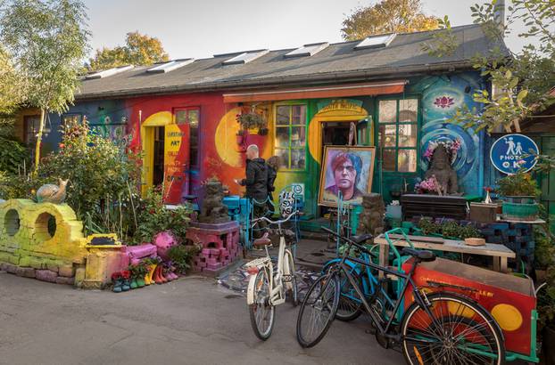 COPENHAGEN, DENMARK - October 2018: Small, colorful art shop in Freetown Christiania, a self-proclaimed autonomous neighbourhood in Copenhagen. Painting of Kim Larsen. Bicycles parked outside.