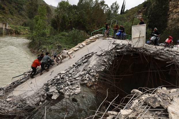 People cross a damaged bridge in Zrarieh