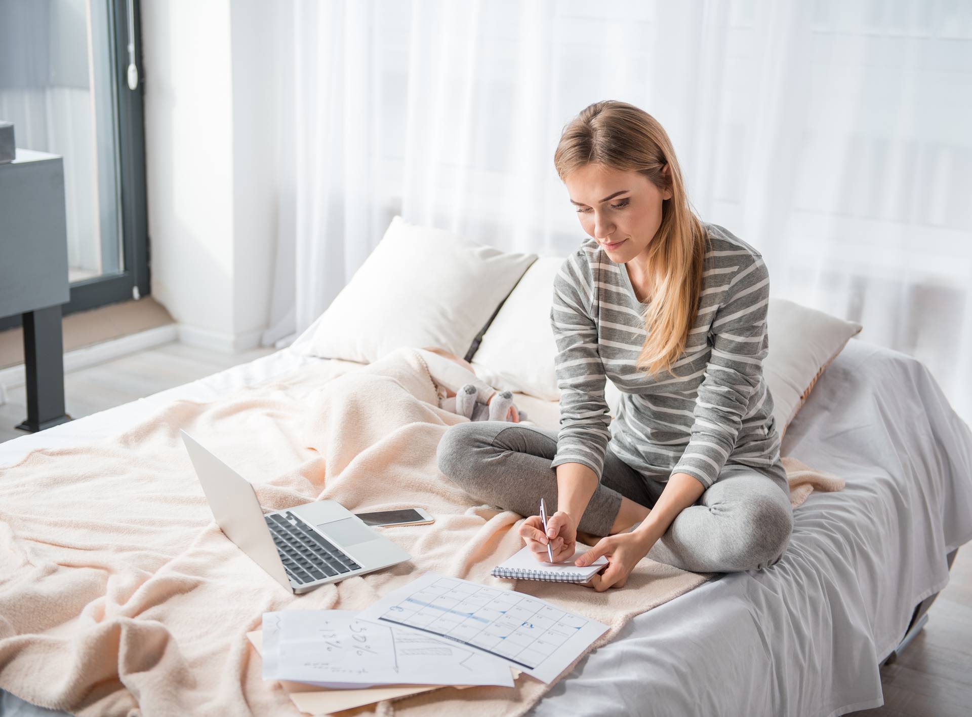 Focused female writing in pad near infant