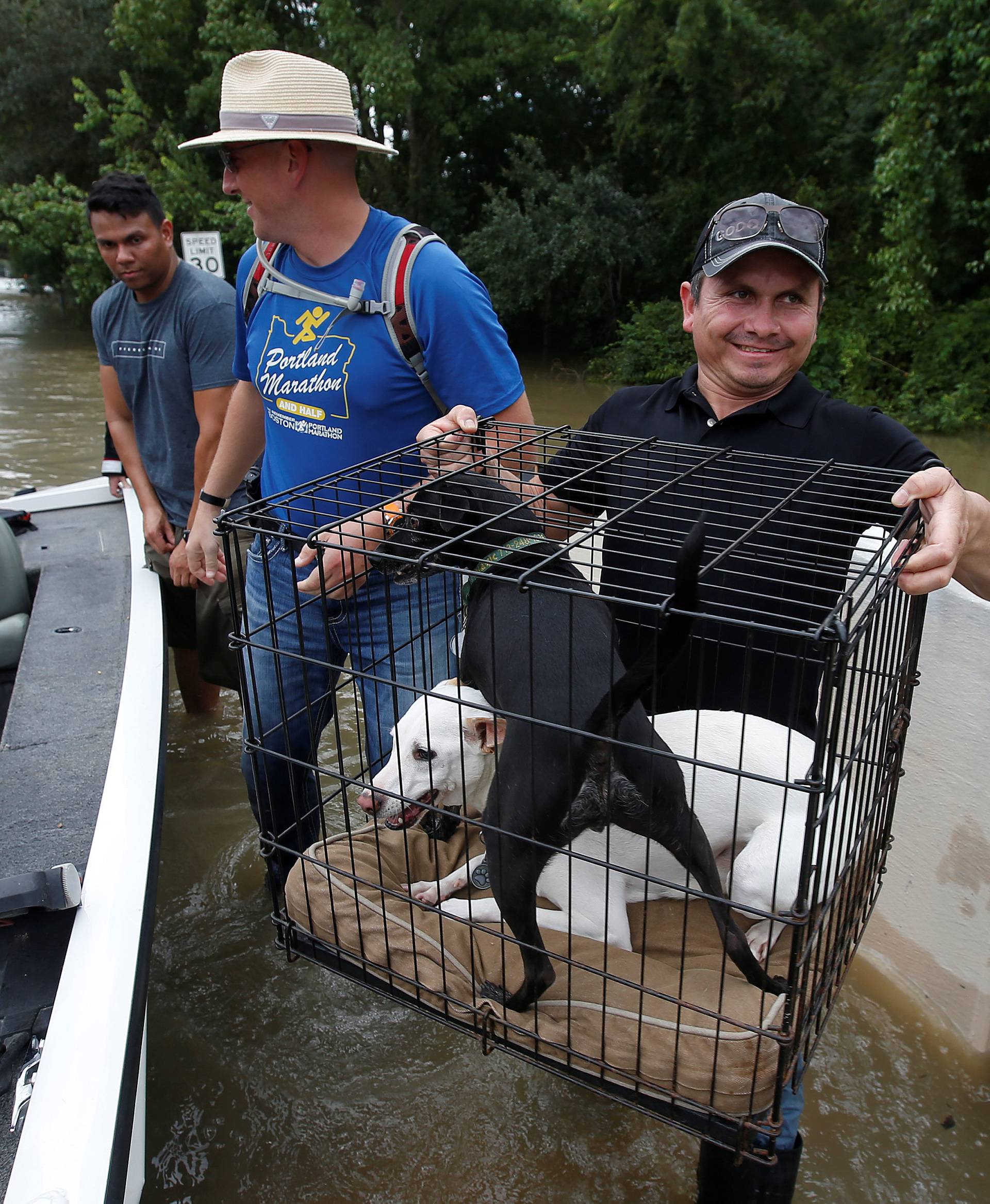 People unload belongings and dogs to cross a bridge as they evacuate from the rising waters of Buffalo Bayou following Hurricane Harvey in a neighborhood west of Houston