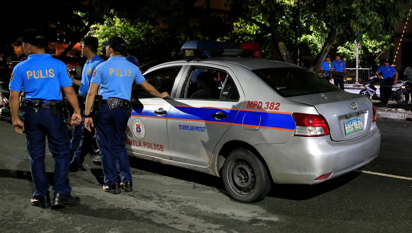 Members of the Philippine National Police (PNP) stand  guard in front of the body of a suspected drug pusher killed in a police operation in Malate city