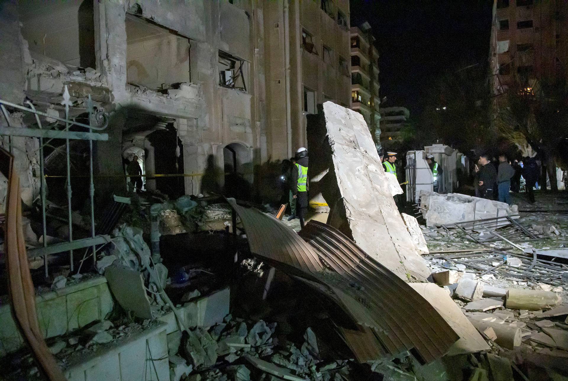 People inspect the damage at the site of a rocket attack, in central Damascus's Kafr Sousa neighbourhood