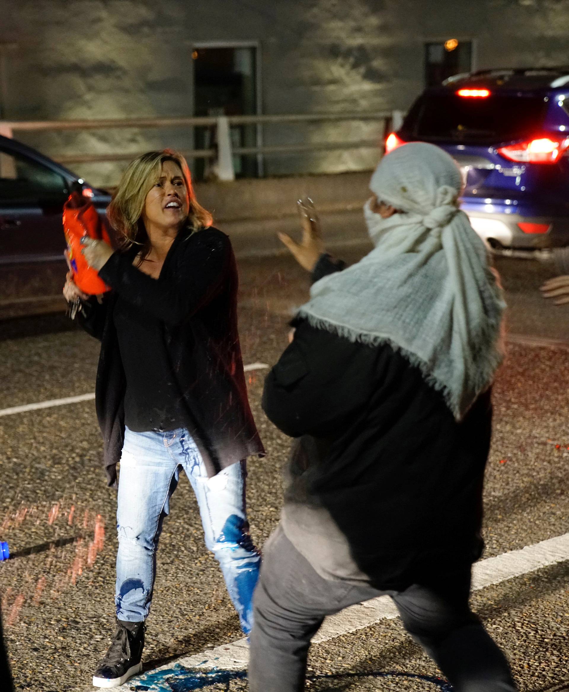 A motorist who was caught in the middle of a riot threatens a demonstrator with detergent during a protest against the election of Republican Donald Trump as President of the United States in Portland