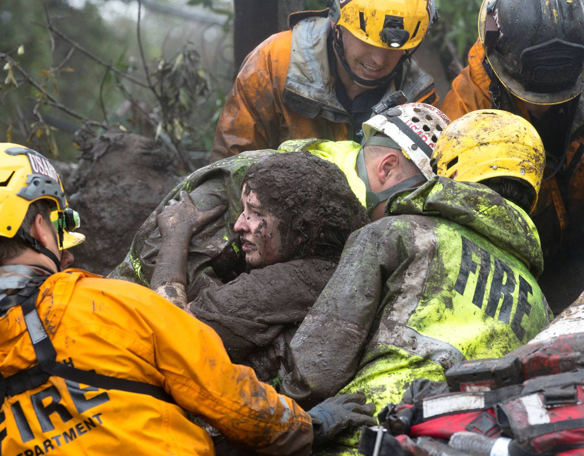 Emergency personnel carry a woman rescued from a collapsed house after a mudslide in Montecito