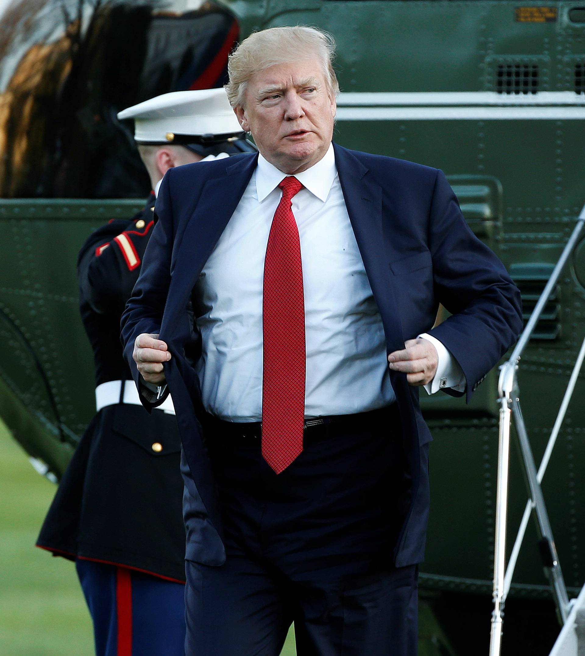 U.S. President Donald Trump adjusts his jacket as he walks from Marine One upon his return to the White House in Washington
