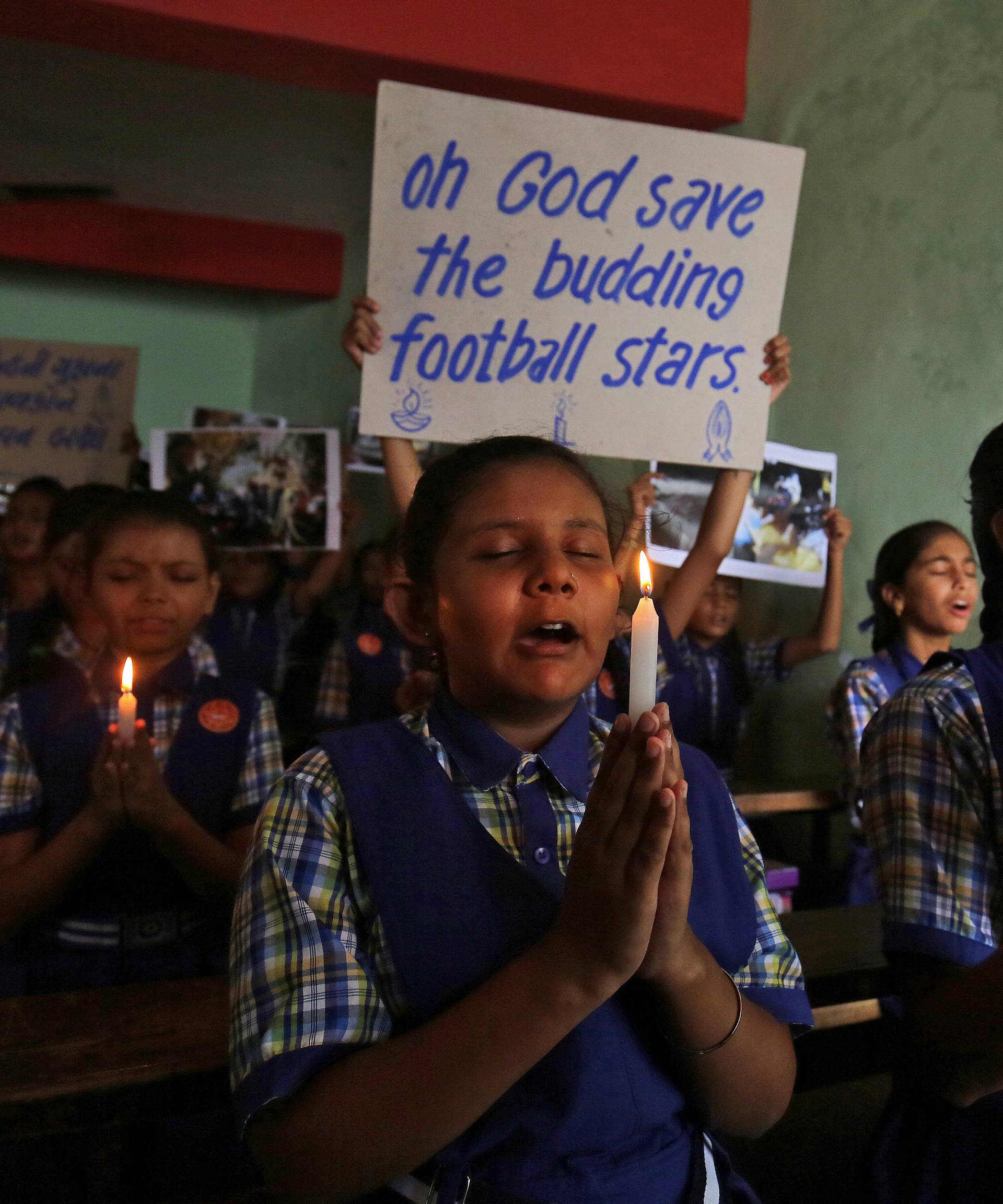 Schoolchildren pray for the schoolboys who are trapped inside a flooded cave in Thailand's northern province of Chiang Rai, at a school in Ahmedabad