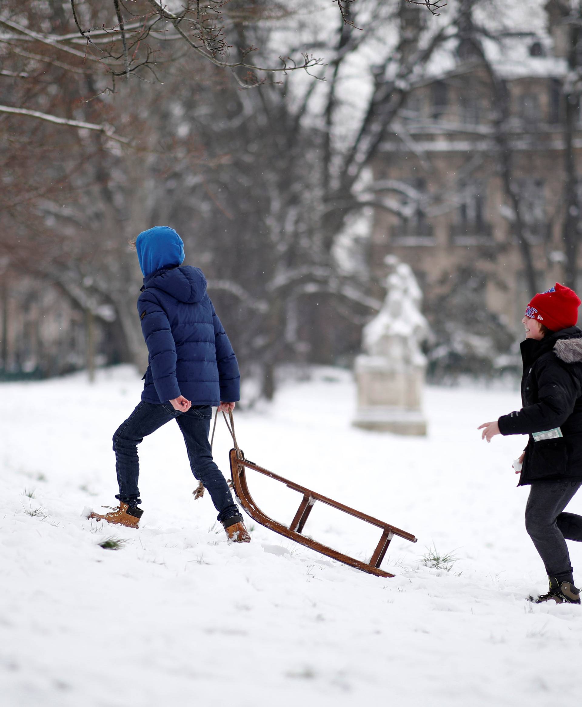 Youths play after a fresh snowfall in the Parc Monceau as winter weather bringing snow and freezing temperatures continues in Paris