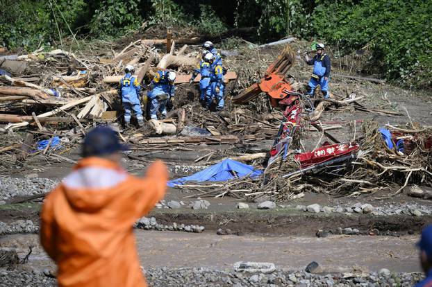 Workers conduct a search operation for missing people around debris following floods caused by torrential rain in Wajima