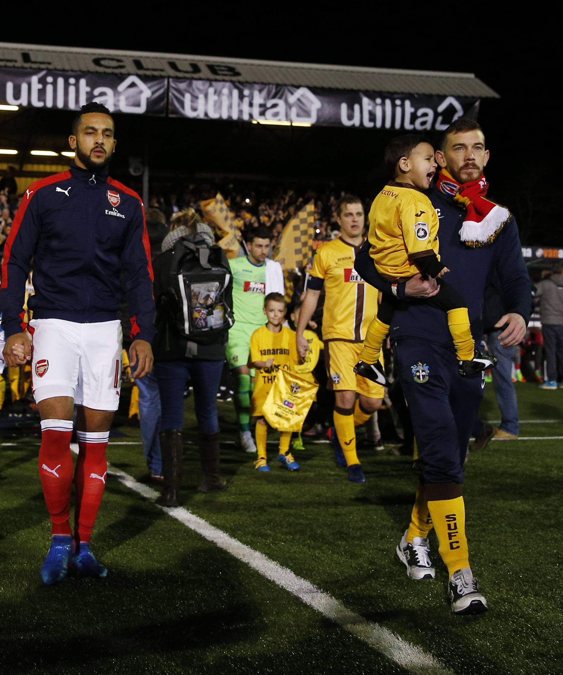 Arsenal's Theo Walcott and Sutton United's Jamie Collins lead out their teams before the match