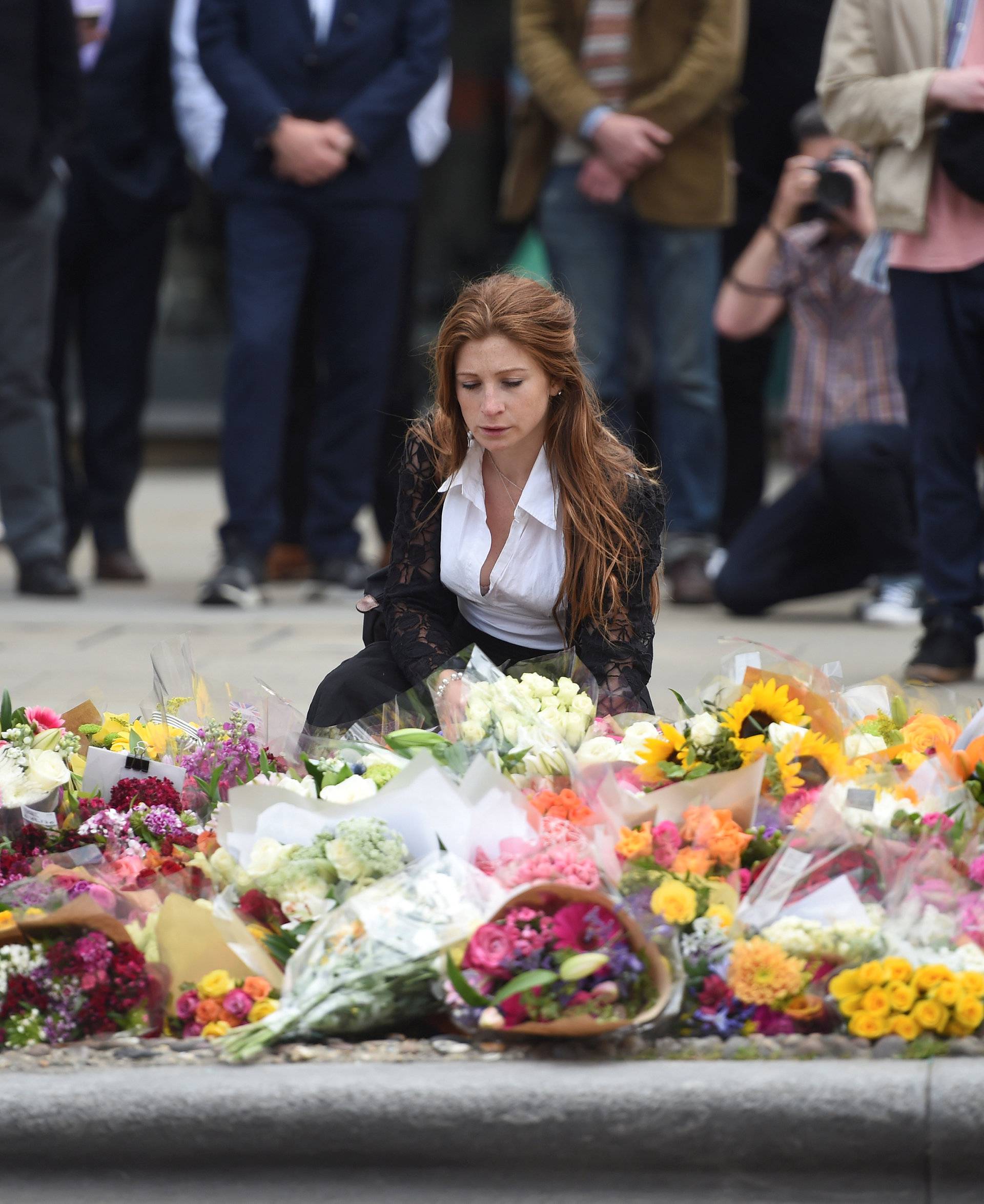 A woman reacts next to flowers left on the south side of London Bridge near Borough Market after an attack left 7 people dead and ozens of injured in London