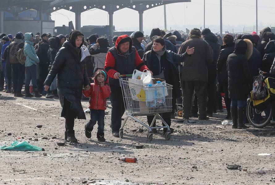 People stand in a line during the distribution of humanitarian aid in the besieged city of Mariupol