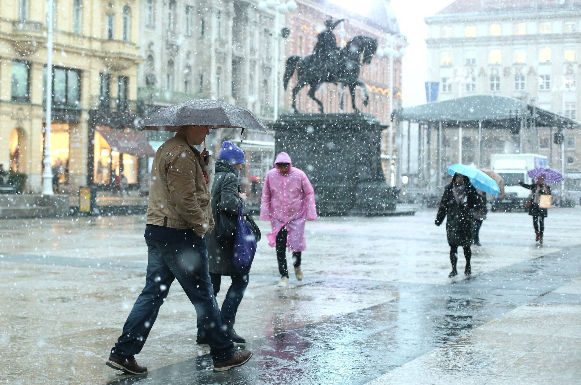 Zagreb: Gra?ani se na glavnom Trgu štite kišobranima od prvog gustog snijega