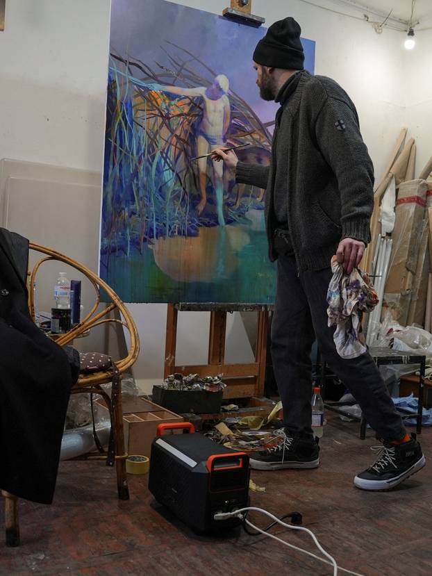 Ukrainian artist works at his studio during a power blackout in Kyiv