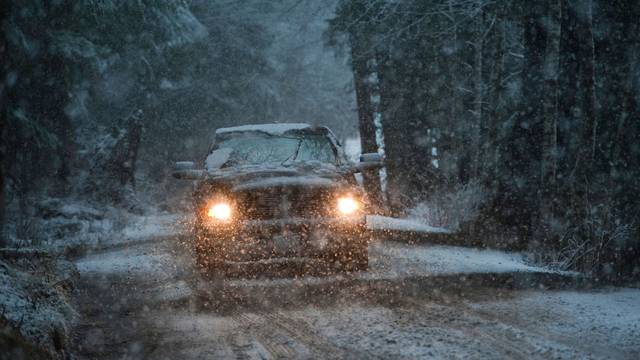 Sport utility vehicle driving in a snow storm near Sitka, Alaska, USA