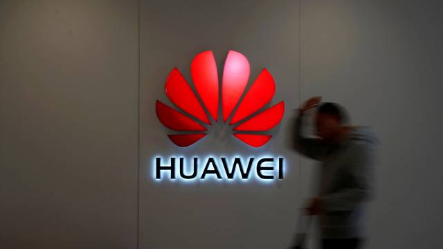 FILE PHOTO: Man walks by a Huawei logo at a shopping mall in Shanghai