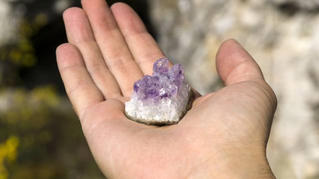 natural crystals of amethyst on the human palm