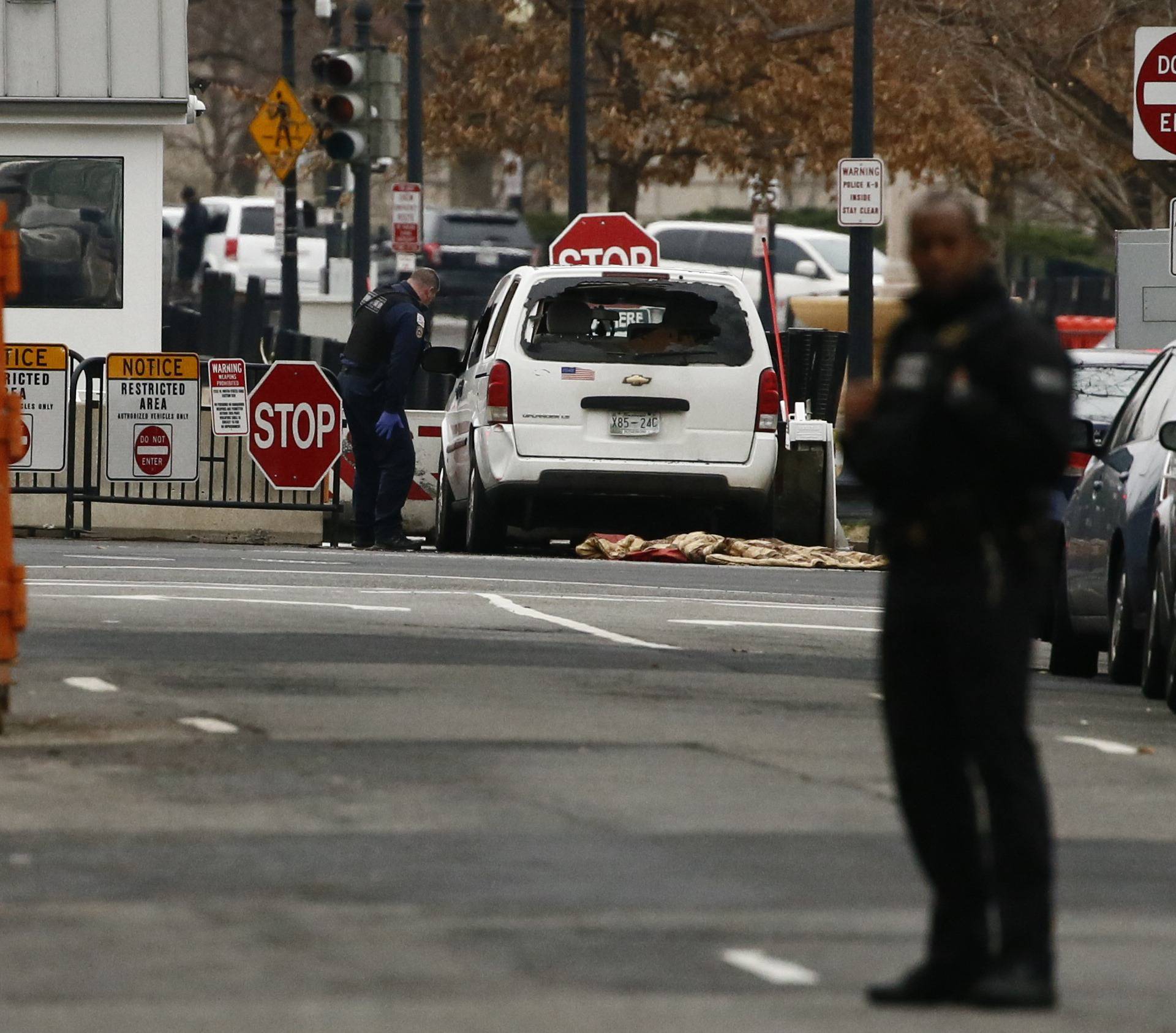 Uniformed U.S. Secret Service officers investigate passenger vehicle that struck a security barrier near the White House in Washington