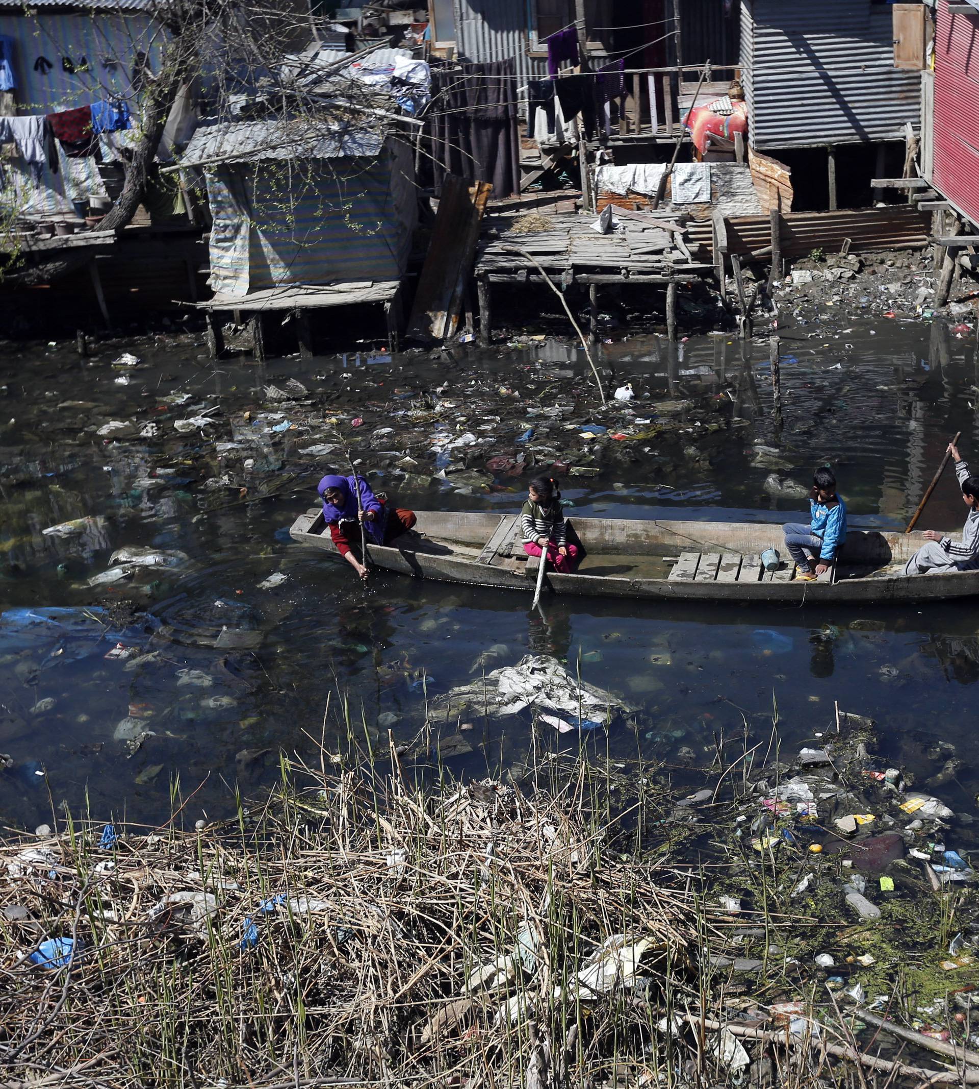 A Kashmiri family looks for scrap wood in a polluted canal near Srinagar in the Kashmir region of India