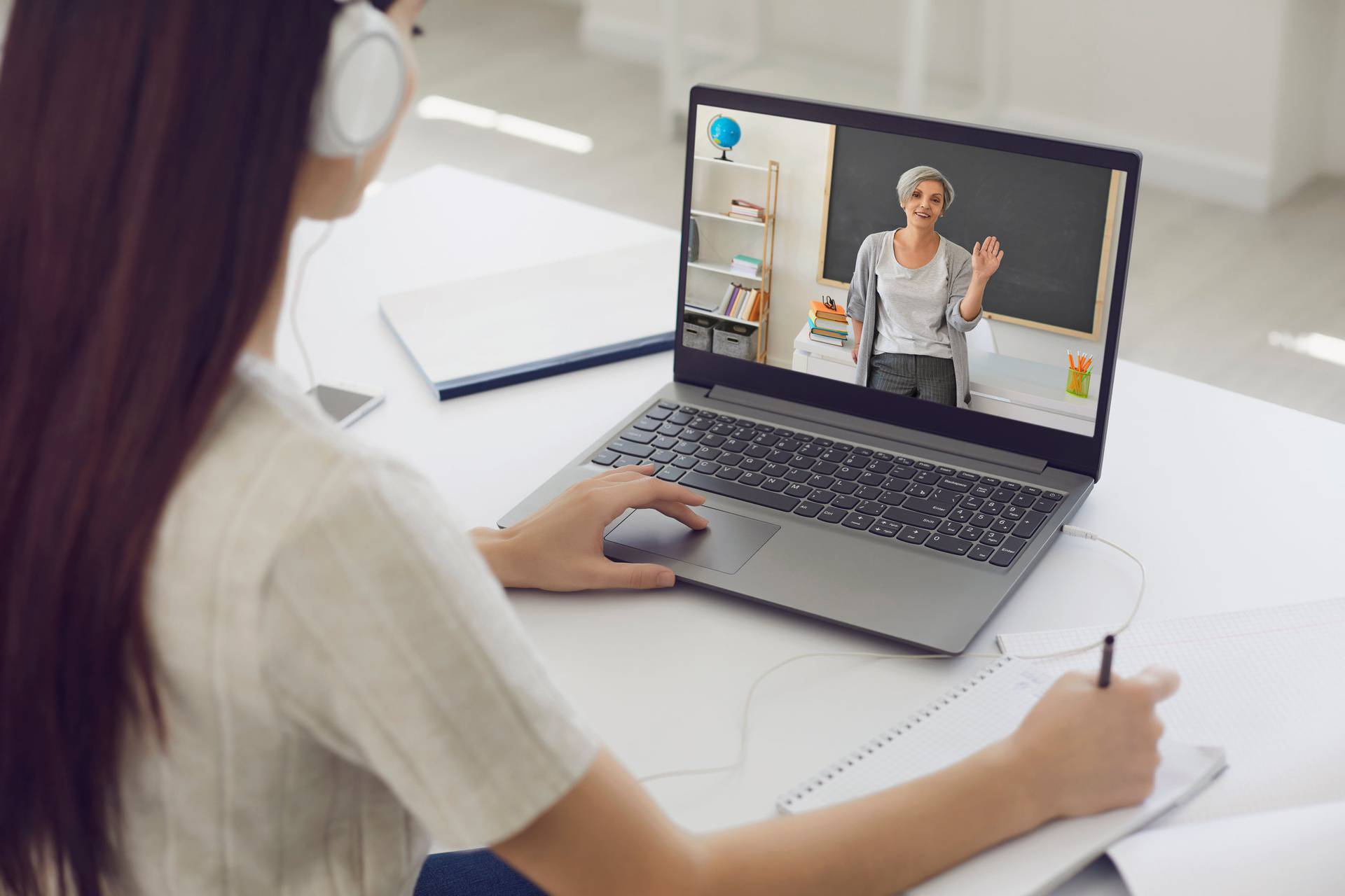 Learning education course lecture online. Girl student in headphones listens to the teacher video chat application remotely at home