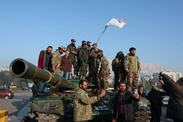 Rebel fighters stand on a tank,, in Damascus