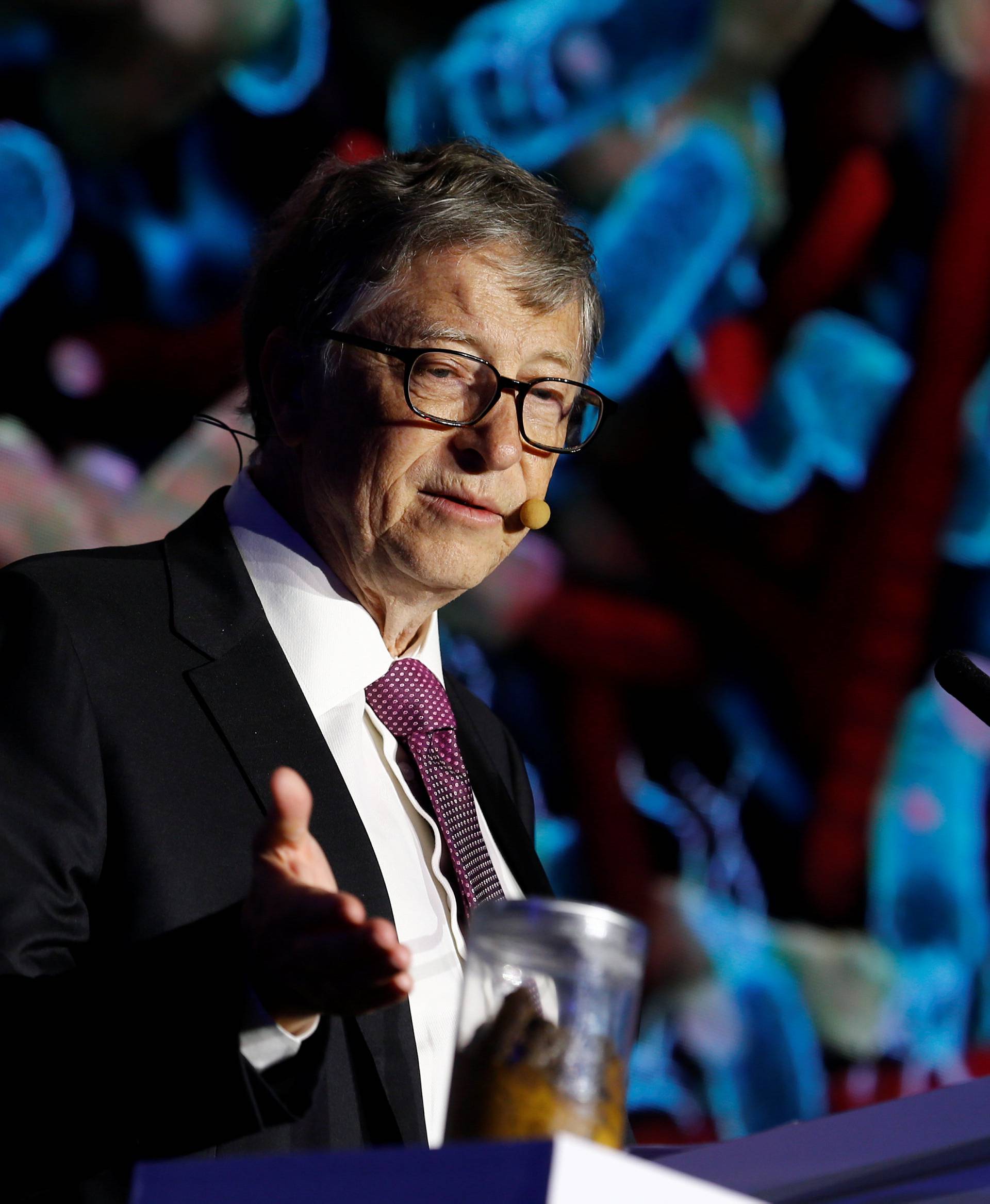 Microsoft founder Bill Gates points at a jar containing human faeces during his speech at the Reinvented Toilet Expo showcasing sewerless sanitation technology in Beijing