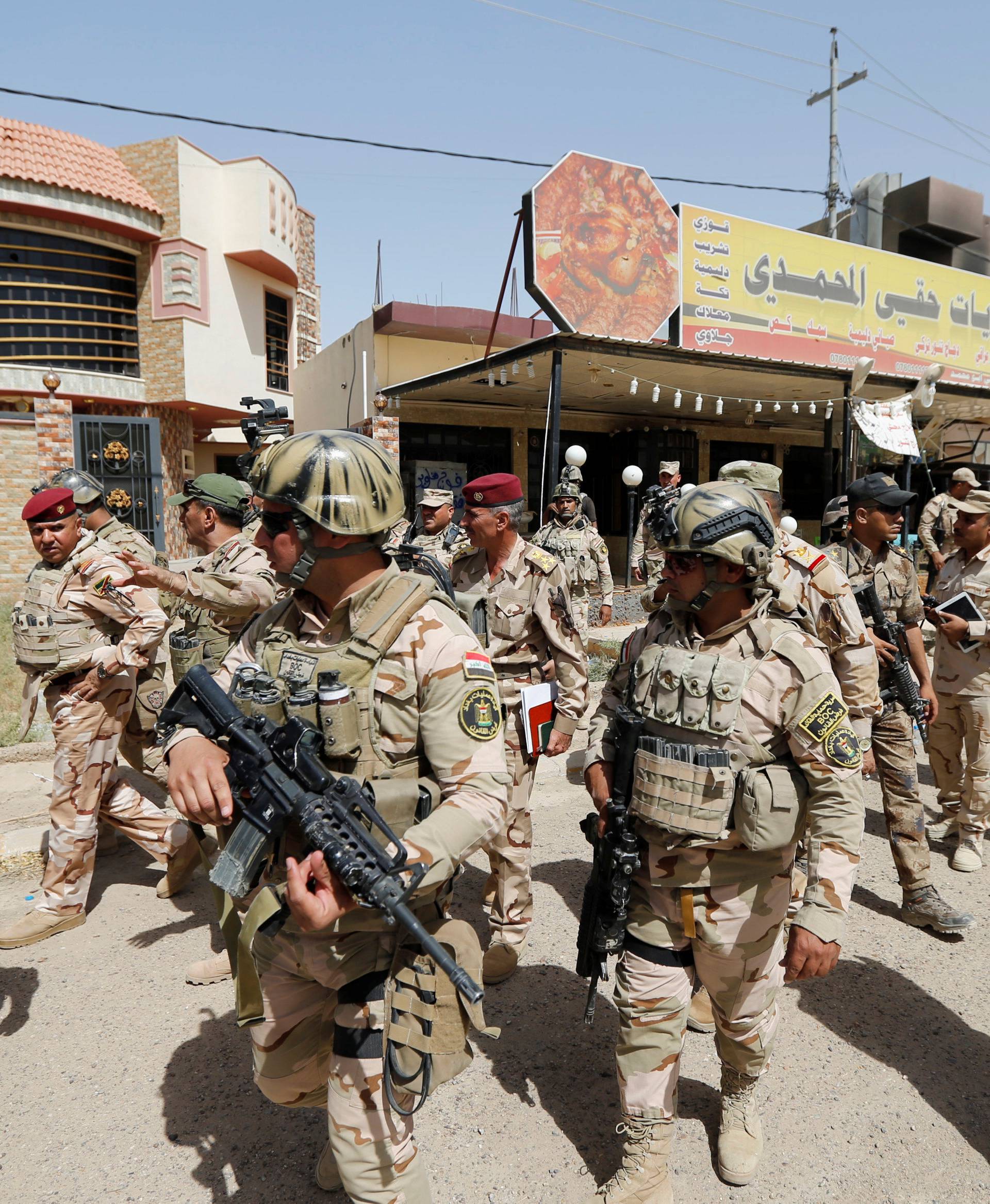 Iraqi army soldiers walk with their weapons in center of Falluja